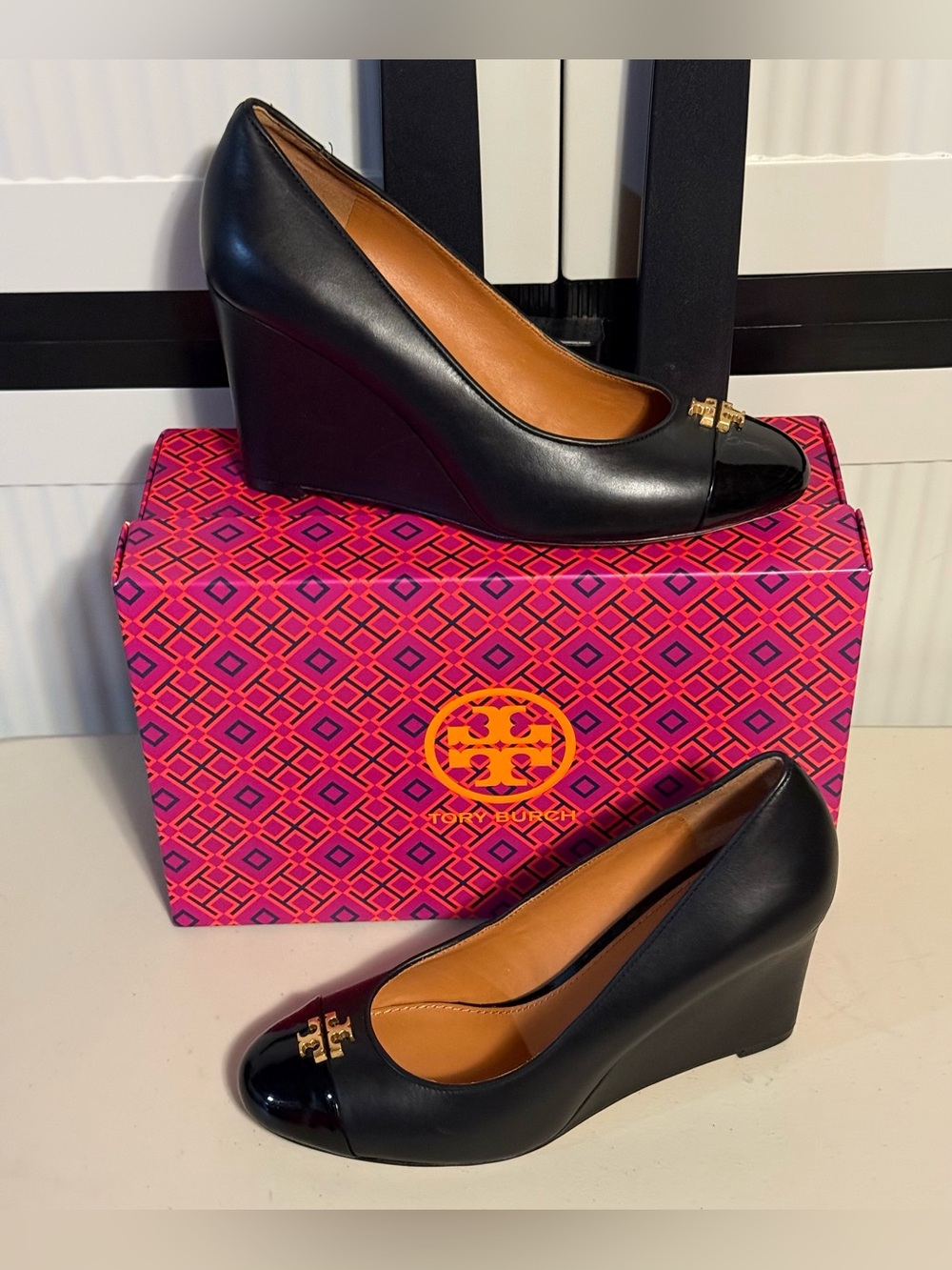 Tory Burch “Everly” Black Leather/Patent Cap Toe Wedge Pumps with Gold Logo